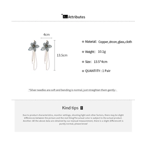 Detailed view of long tassel earrings with gray-blue fabric flowers and dimensions info
