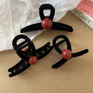 Detailed view of elegant black flocked hair claws set featuring large red beads accent