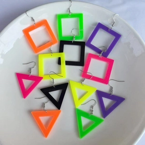 Neon acrylic geometric earrings in square and triangle shapes displayed on a white plate