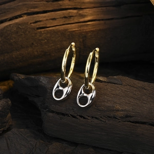 Detail of silver S925 pull-tab pendant and golden hoop earring on dark wood background