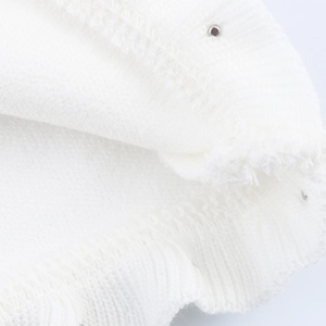 Detailed macro view of white knitted fabric texture with fringe edges and metal eyelets