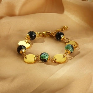 Vintage gold metal disc and green resin bead bracelet on luxurious gold silk background