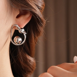 Detail of twisted silver metal ball earrings on model with high gloss finish