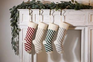 Close-up of four knitted striped Christmas stockings hanging on a white fireplace mantle
