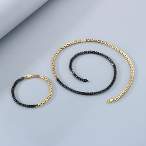 Detail of minimalist two-tone gold and black stainless steel necklace and bracelet set