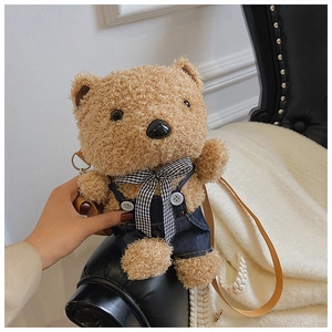 Detail of cute brown plush teddy bear bag in denim overalls with a checkered bowtie
