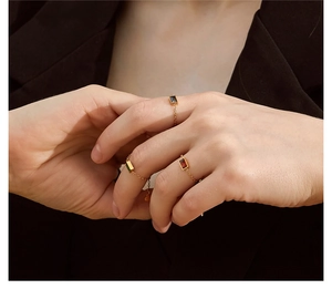 Detail of adjustable gold chain rings with emerald, ruby, and onyx rectangular zircons