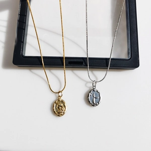 Detailed macro view of the double-sided mermaid relief on gold and silver necklaces