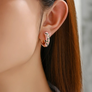 Detail of pink enamel flower hoop earring worn by a model in a close-up profile view