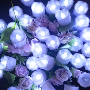 Detail view of white LED candles with purple and pink artificial roses for party decor