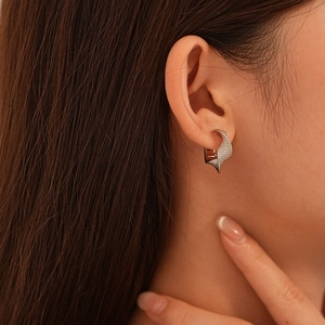 Close-up of minimalist silver twisted hoop earring on model with textured metallic finish
