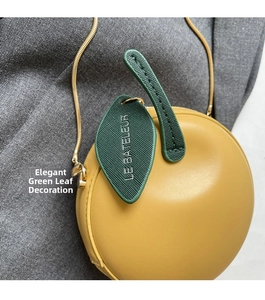 Detail of yellow apple-shaped bag with green leather leaf and gold chain strap