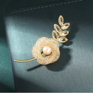 Macro shot of a golden floral brooch with fine mesh texture, pearl and crystal accents