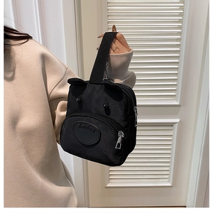 Detail of cute black nylon puppy handbag with 3D ears and front zipper pocket