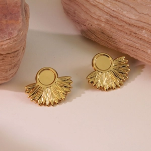 Detailed macro view of vintage gold fan-shaped earrings on natural stone background