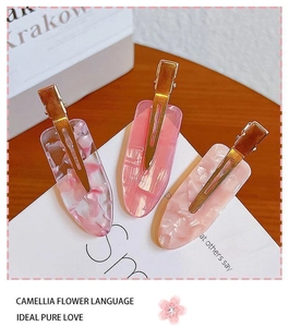 Detailed macro view of pink acrylic hair clips with a gradient finish and gold metal base