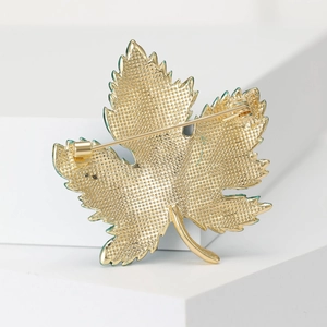 Elegant gold maple leaf brooch with sparkling rhinestones shown from a detailed front angle