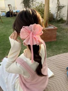 Close-up of pink lace scrunchie with silk ribbon bow on a person's hair in sunlight