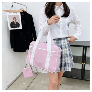 Detail view of pink JK uniform bag with heart-shaped transparent window and mini pouch