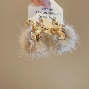 Close-up of golden flower stud earrings with beige pompom detail and S925 silver pins