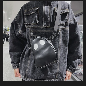 Detail shot of a black cartoon ghost crossbody bag worn on the chest with adjustable strap
