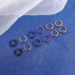 Detailed flat lay of stainless steel hoop earrings in six metallic colors on blue fabric