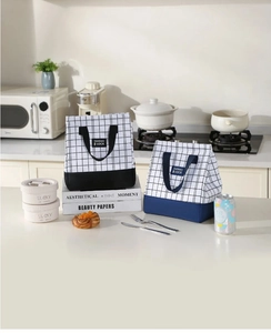 Detail view of reinforced handles and thermo lock labels on plaid insulated lunch bags
