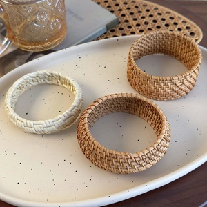Detailed view of handmade woven rattan bangles in natural tones on a white ceramic plate