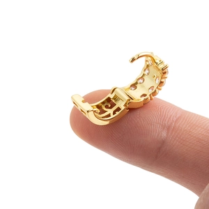 Hinged gold cartilage hoop earring with sparkling clear stones held on fingertip