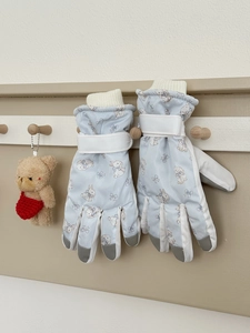 Detail of light blue ski gloves with rabbit prints, wrist straps and windproof cuffs