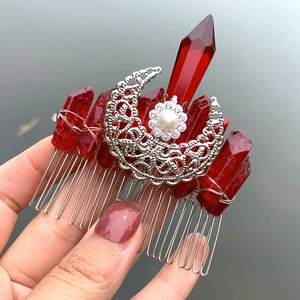 Detailed shot of handmade silver hair comb with red crystals and crescent moon charm