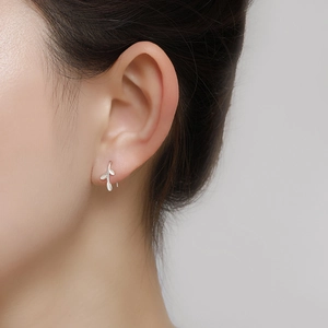 Detail of S999 sterling silver ginkgo leaf stud earring worn on model earlobe