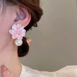 Close-up of pink resin flower earrings with white pearl pendant worn by a model