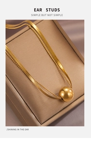 Detailed close-up of a double-layer gold titanium necklace with a polished sphere pendant