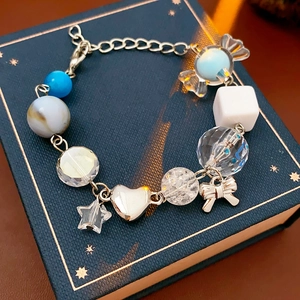 Detailed close-up of beaded bracelet with blue stars and silver butterfly charms on a book