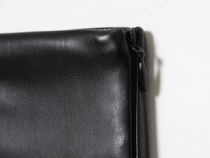Détail de la texture en similicuir noir mettant l'accent sur les coutures et le zip