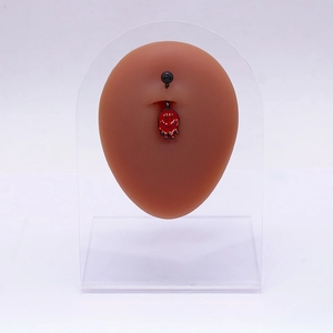 Détail d'un piercing de nombril smiley rouge fondu sur modèle avec tige en acier noir