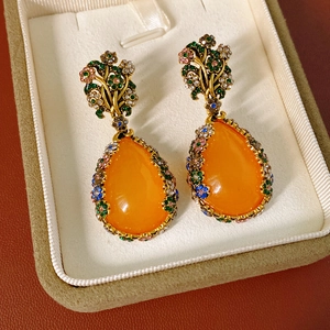 Detail of vintage teardrop earrings with orange stones and colorful rhinestones