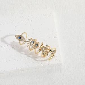 Five-piece golden Evil Eye ring set with blue and clear zircon stones on a stone base