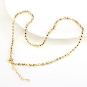Detailed view of polished golden bead necklace with lobster clasp and extension chain