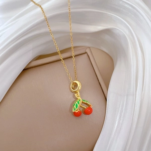 Détail du pendentif cerise en émail rouge et feuilles vertes sur chaîne dorée