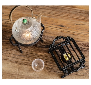 Détail d'un chauffe-plat rétro en fonte avec théière en verre texturé et poignée en rotin