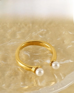 Détail macro d'une bague ouverte en acier inoxydable doré 18 carats avec deux perles