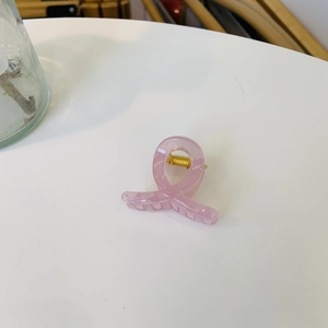 Detailed view of pink translucent acrylic hair claw clip with golden metal spring