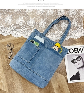 Dettaglio borsa tote in denim blu con tasche frontali e oggetti quotidiani su pavimento legno