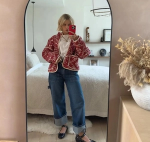 Close-up of a floral quilted jacket with wide-leg jeans in a home mirror selfie look