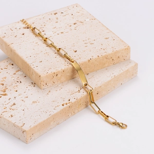 Minimalistisches goldenes Edelstahlarmband mit polierter ID-Platte auf Steinstufen