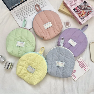 Flat lay of colorful quilted shell makeup bags with ribbon handles in pastel colors