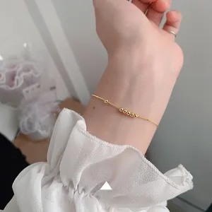 Minimalist gold 925 sterling silver chain bracelet with five small beads on a female wrist