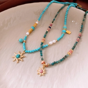 Macro view of bohemian beaded necklaces with sun pendants and natural stones in a tray